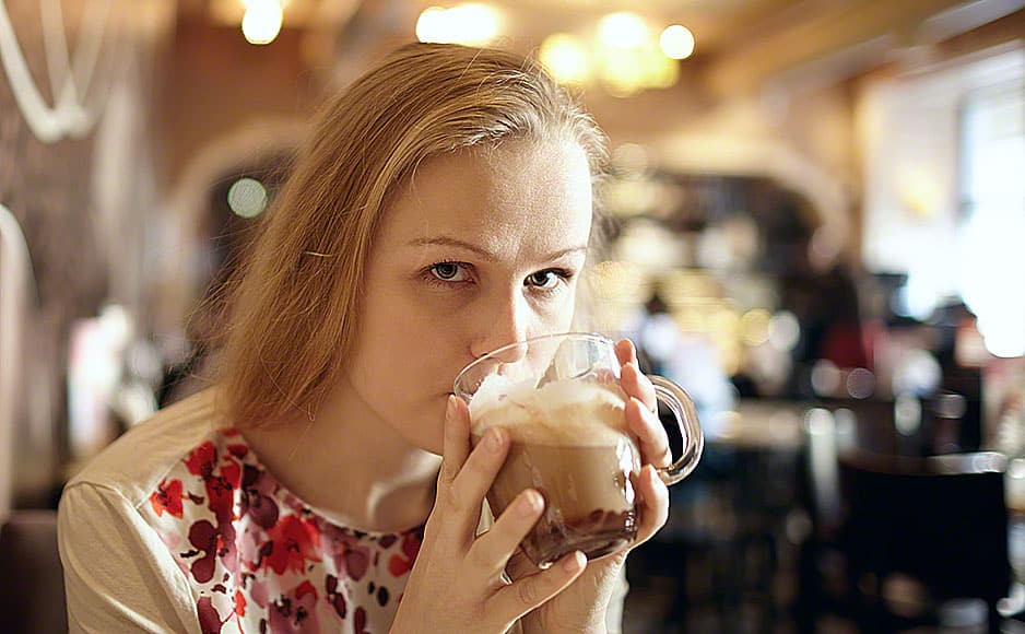 Girl is drinking latte in cafe.