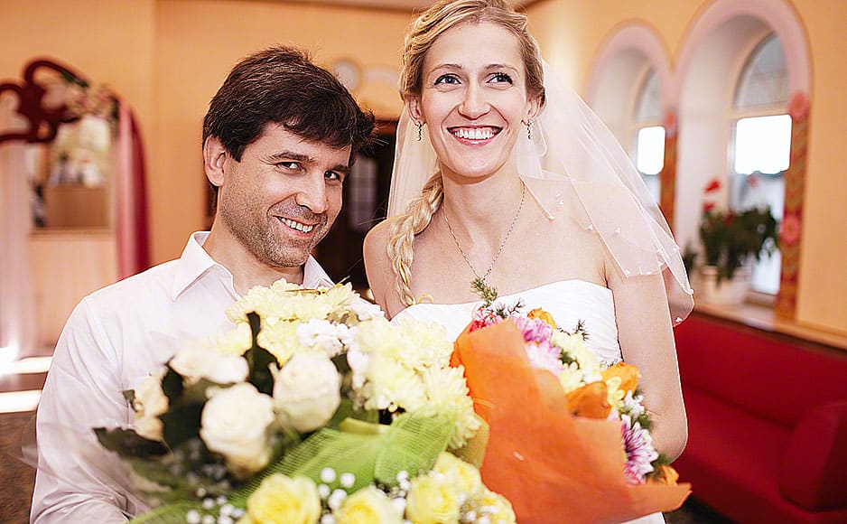 Smiling bride and groom with bouquets of flowers
