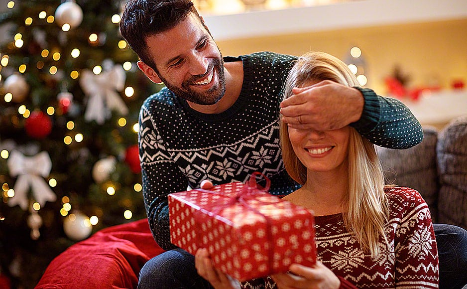 Guy covering his girlfriend’s eyes while giving her present