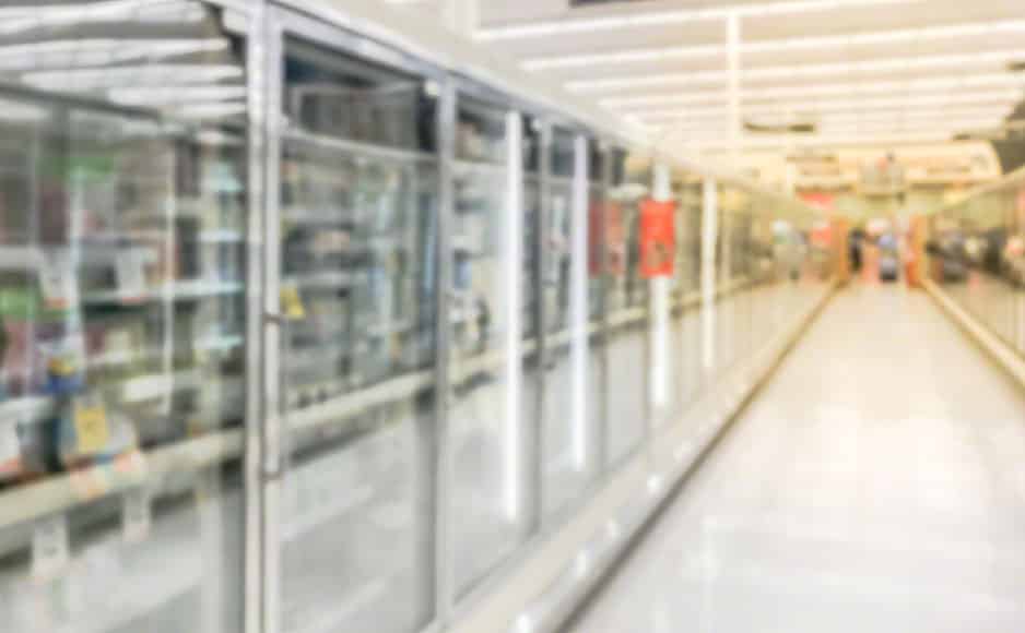 Blurry background low angle view transparent fridge with frozen food section at grocery store