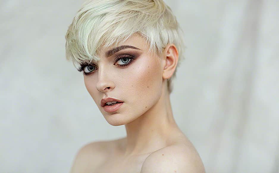 Beautiful blond woman with short hair and evening make-up looking at camera