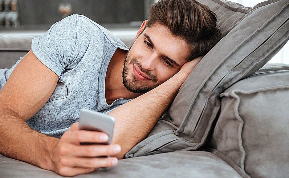 Young man chatting while lies on sofa